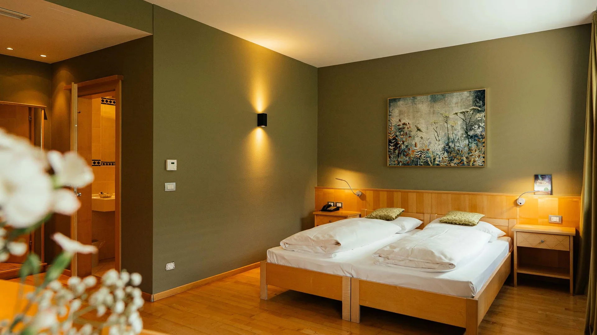 Der Lodenwirt in Vintl | Hotel, Residence & Restaurant Gemütliches Hotelzimmer mit zwei Einzelbetten und warmem Licht