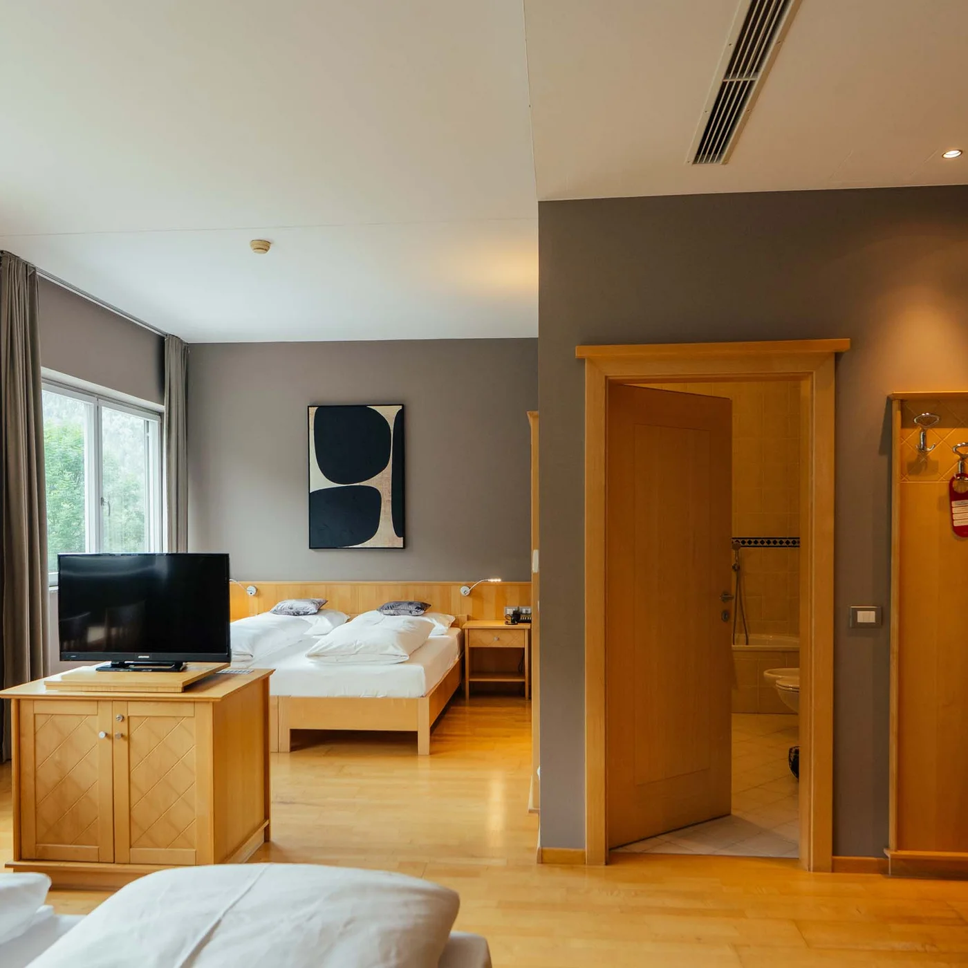 Der Lodenwirt in Vintl | Hotel, Residence & Restaurant Helles Hotelzimmer mit Doppelbett, Fernseher, Esstisch und offenem Badezimmer