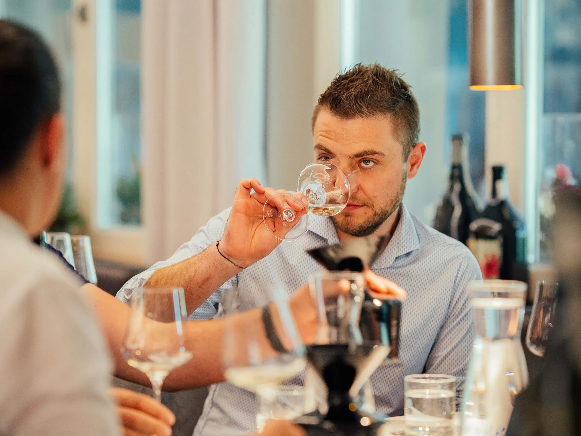 Der Lodenwirt in Vintl | Hotel, Residence & Restaurant Mann riecht an einem Weinglas bei einer Weinverkostung in elegantem Raum