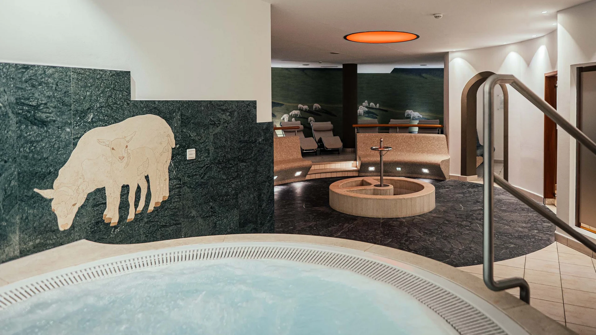 Der Lodenwirt in Vintl | Hotel, Residence & Restaurant Innenbereich mit Whirlpool, Sitzbereich und Schafmosaik an der Wand