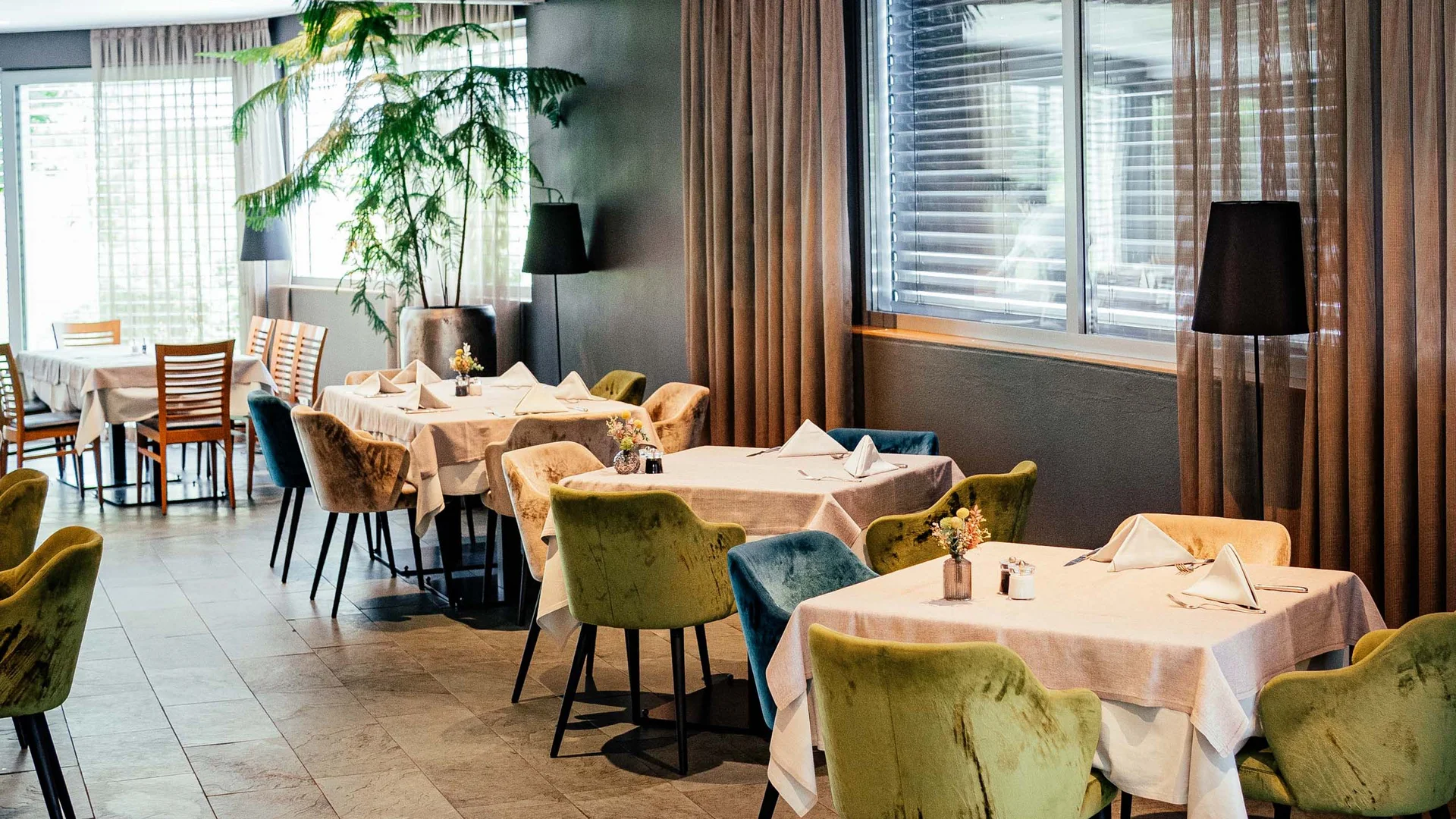 Der Lodenwirt in Vintl | Hotel, Residence & Restaurant Modernes Restaurant mit gedeckten Tischen und bunten Stühlen