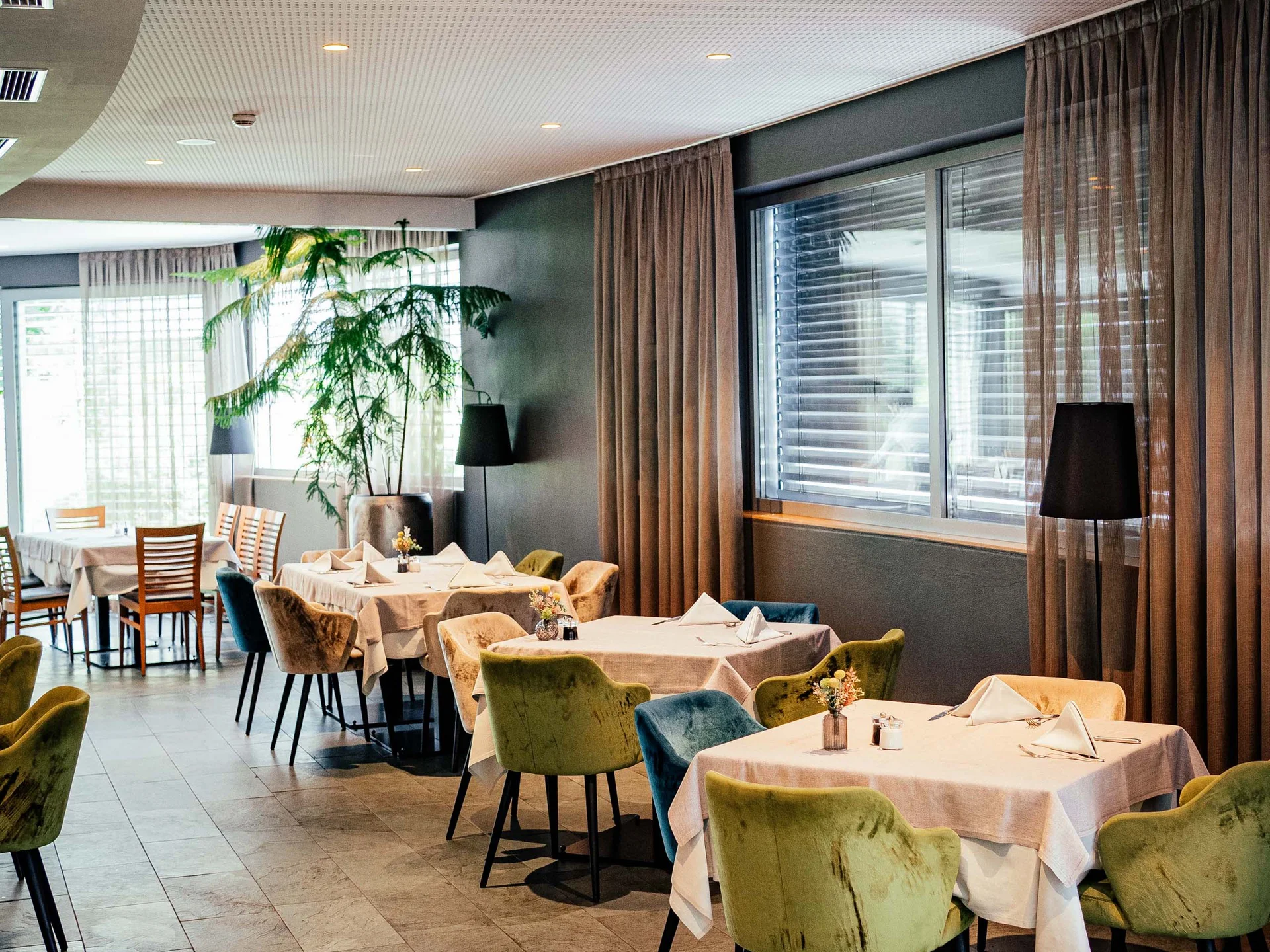Der Lodenwirt in Vintl | Hotel, Residence & Restaurant Modernes Restaurant mit gedeckten Tischen und bunten Stühlen