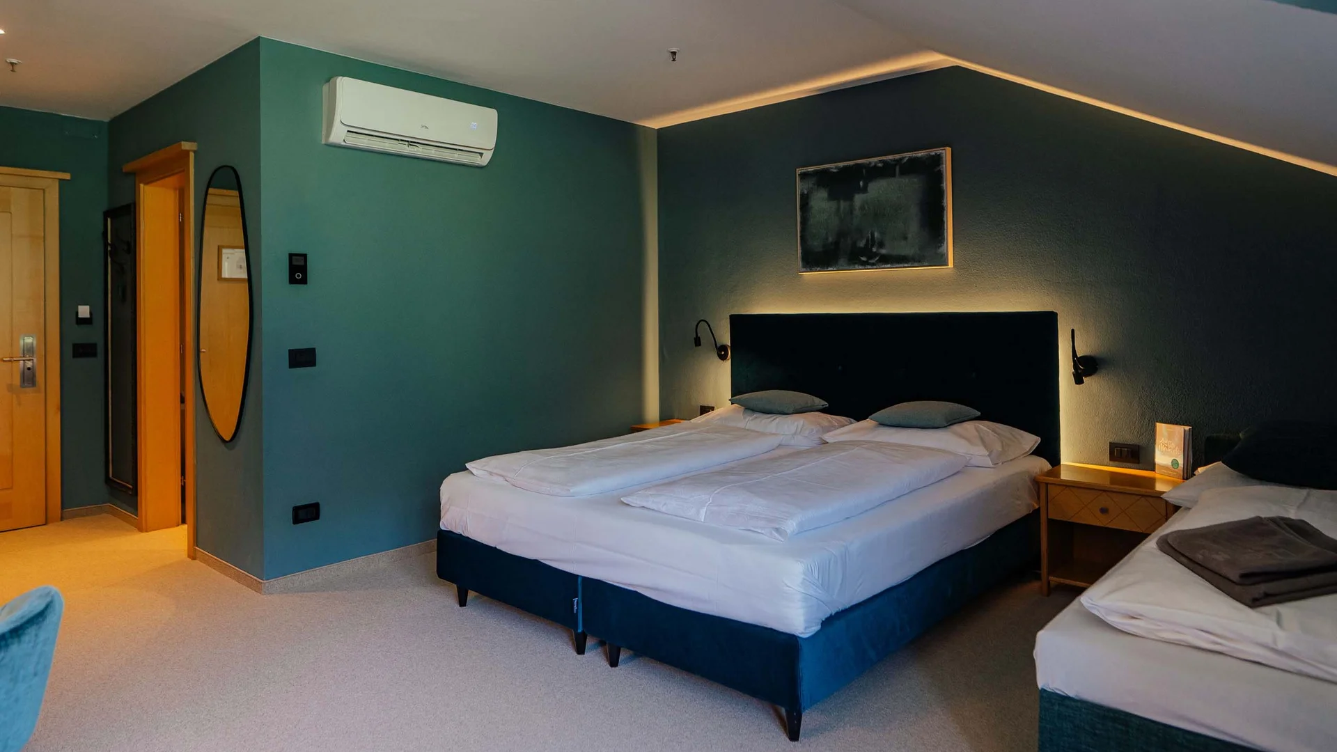 Der Lodenwirt in Vintl | Hotel, Residence & Restaurant Modernes Hotelzimmer mit Doppelbett, Einzelbett und indirekter Beleuchtung