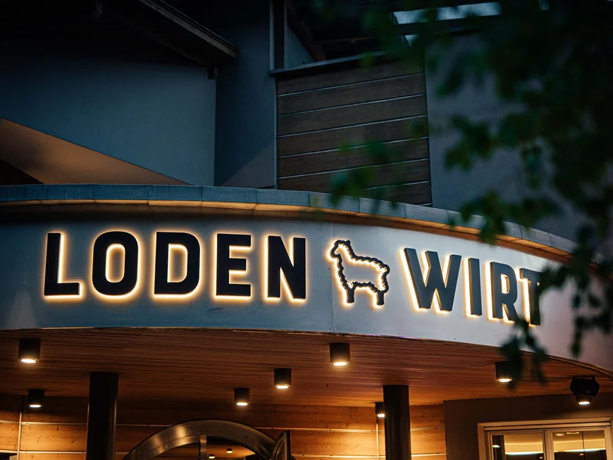 Der Lodenwirt in Vintl | Hotel, Residence & Restaurant Beleuchtetes Schild mit Schriftzug Loden Wirt und Lama-Symbol