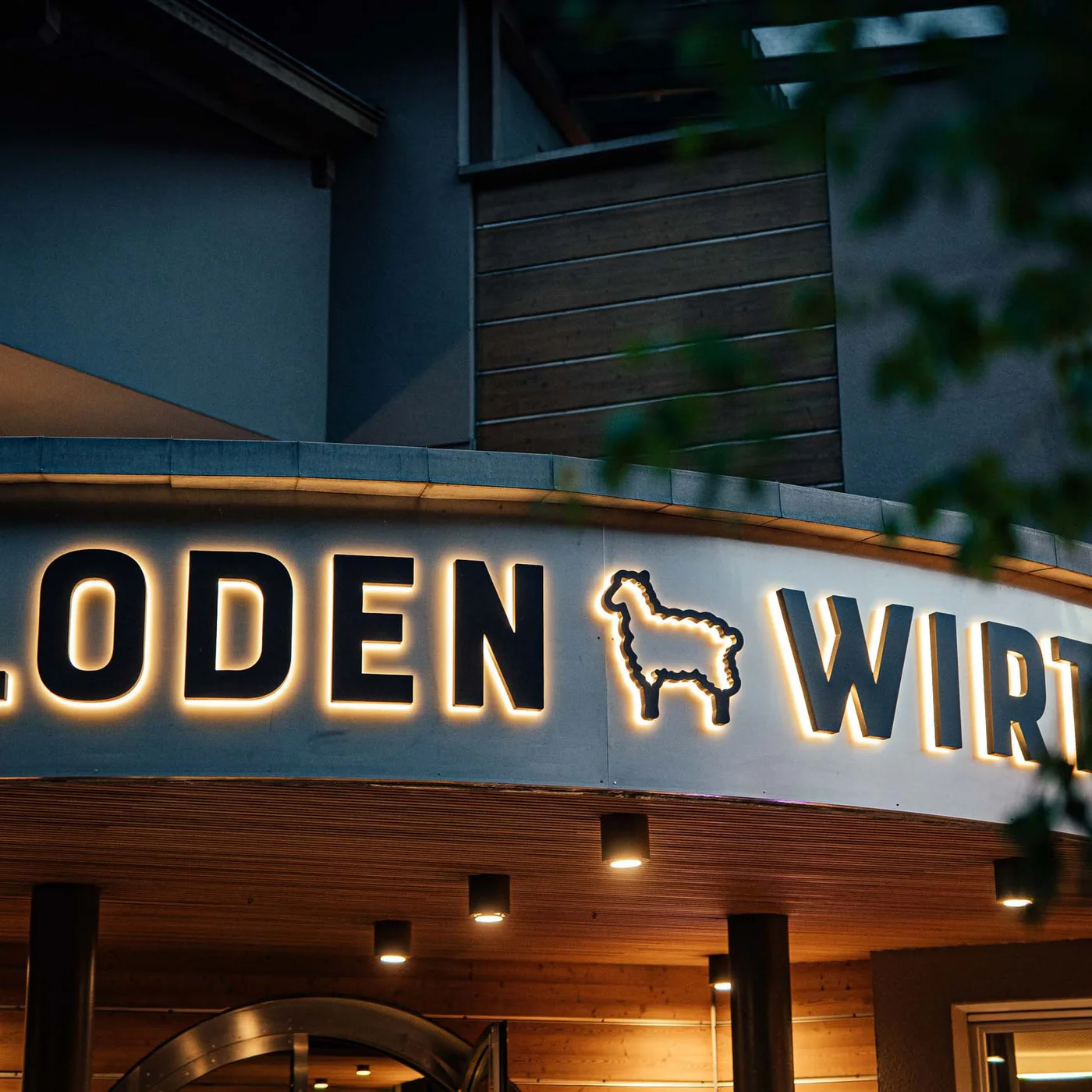 Der Lodenwirt in Vintl | Hotel, Residence & Restaurant Beleuchtetes Schild mit Schriftzug Loden Wirt und Lama-Symbol