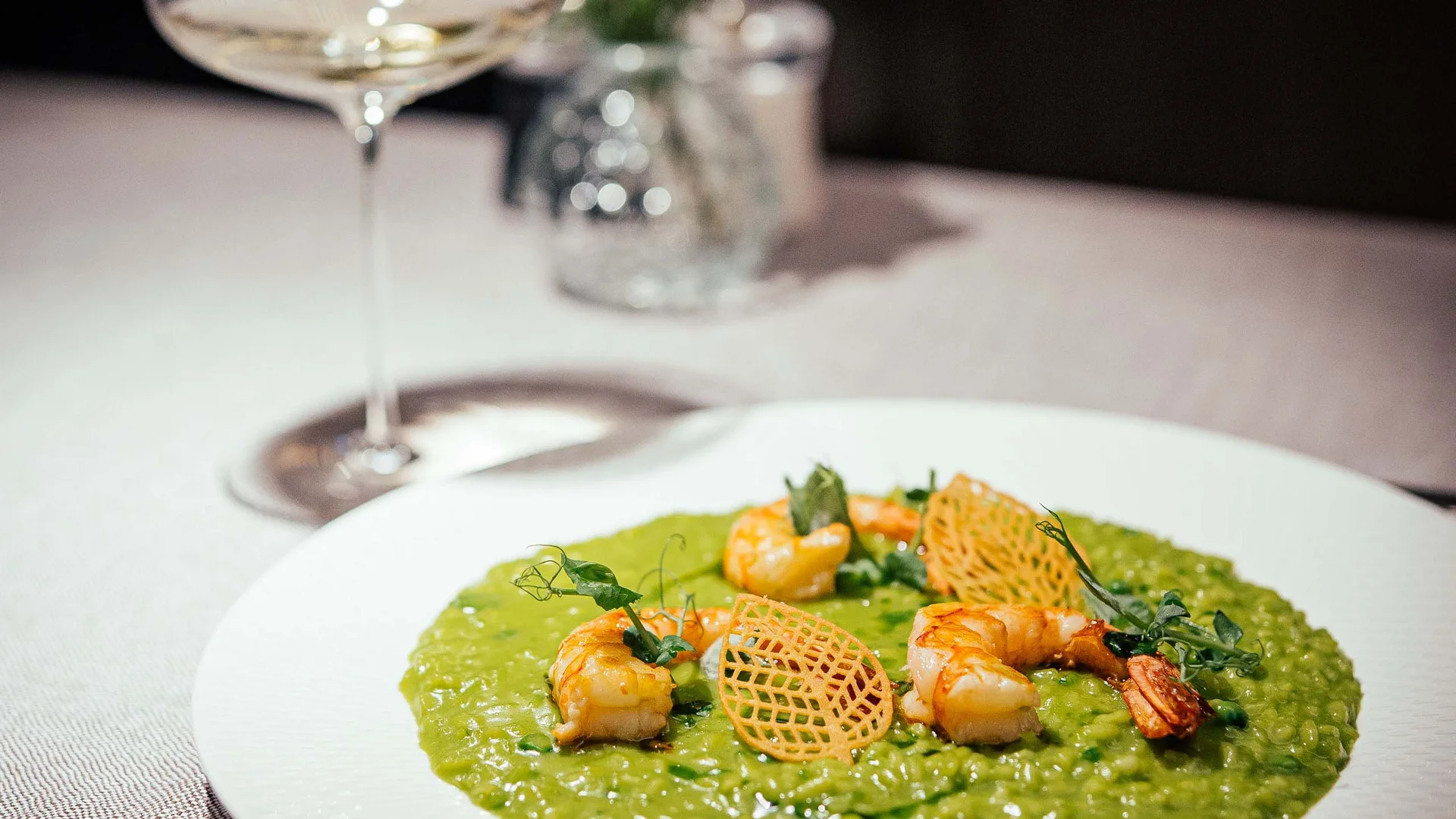 Der Lodenwirt in Vintl | Hotel, Residence & Restaurant Grünes Risotto mit Garnelen und knusprigen Chips auf weißem Teller