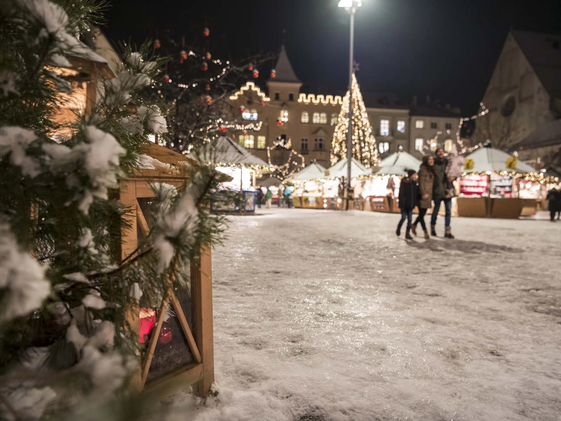 Der Lodenwirt in Vintl | Hotel, Residence & Restaurant Verschneiter Weihnachtsmarkt bei Nacht mit festlich beleuchteten Ständen und Tannenbaum